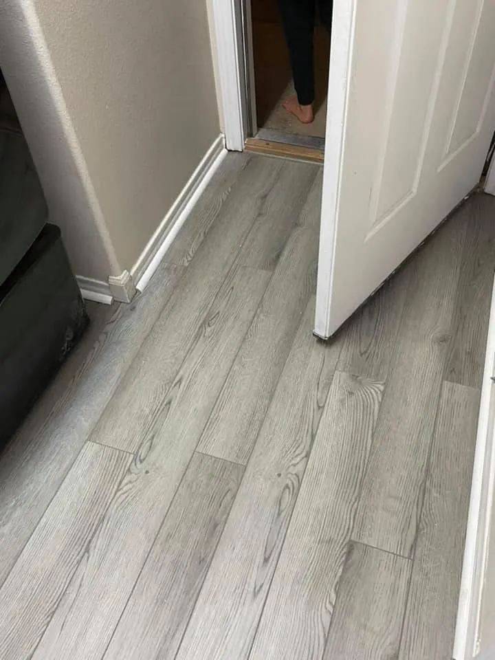 Gray plank flooring finished through a hallway and doorway